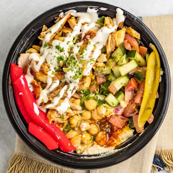 Shawarma Time chicken shawarma bowl with hummus, salad, chickpeas, red peppers, and pickles.