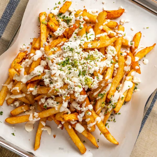 Golden Shawarma Time fries topped with white sauce, crumbled feta cheese, and fresh parsley.